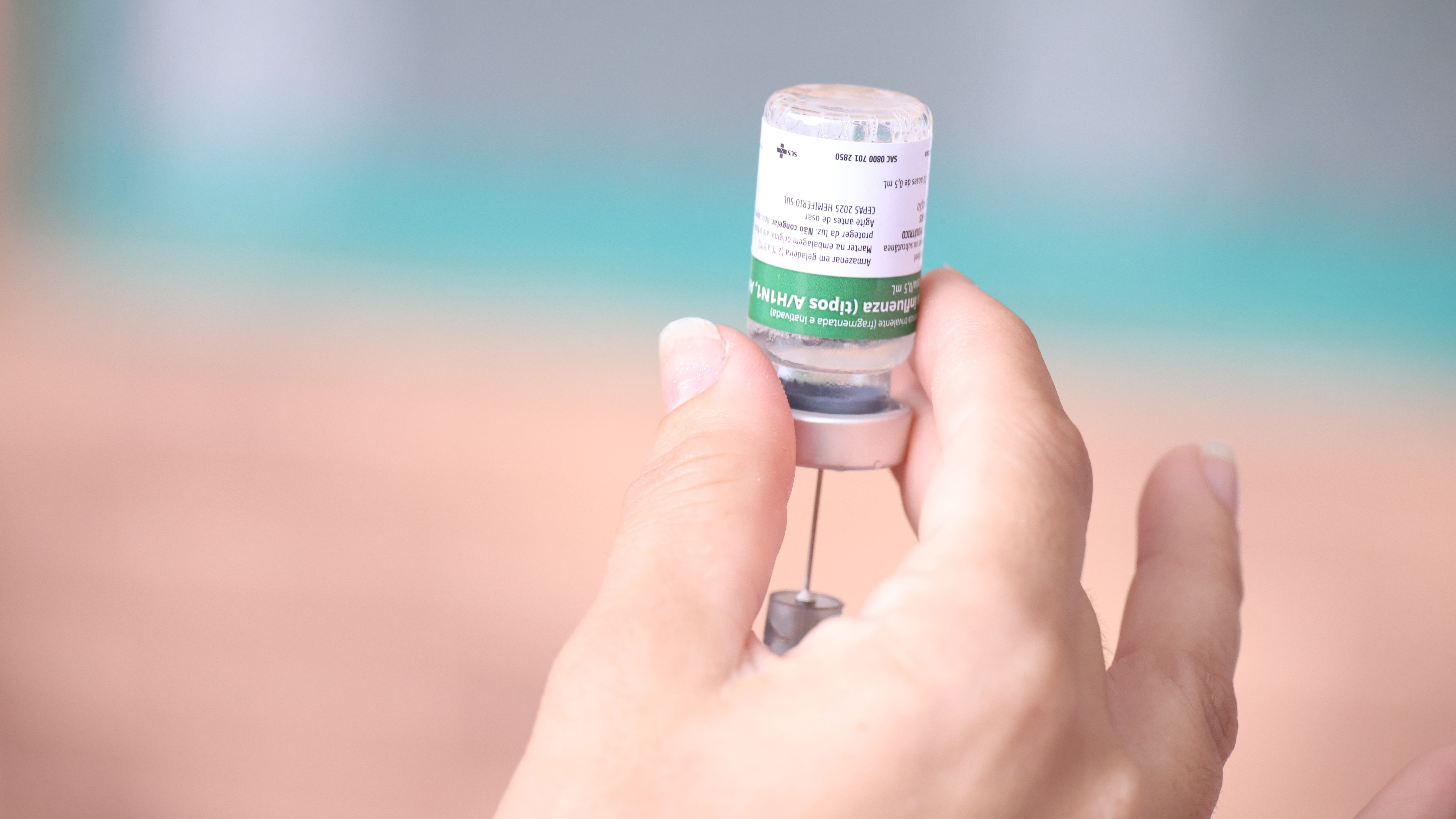 uma mão segurando uma ampola de vacina